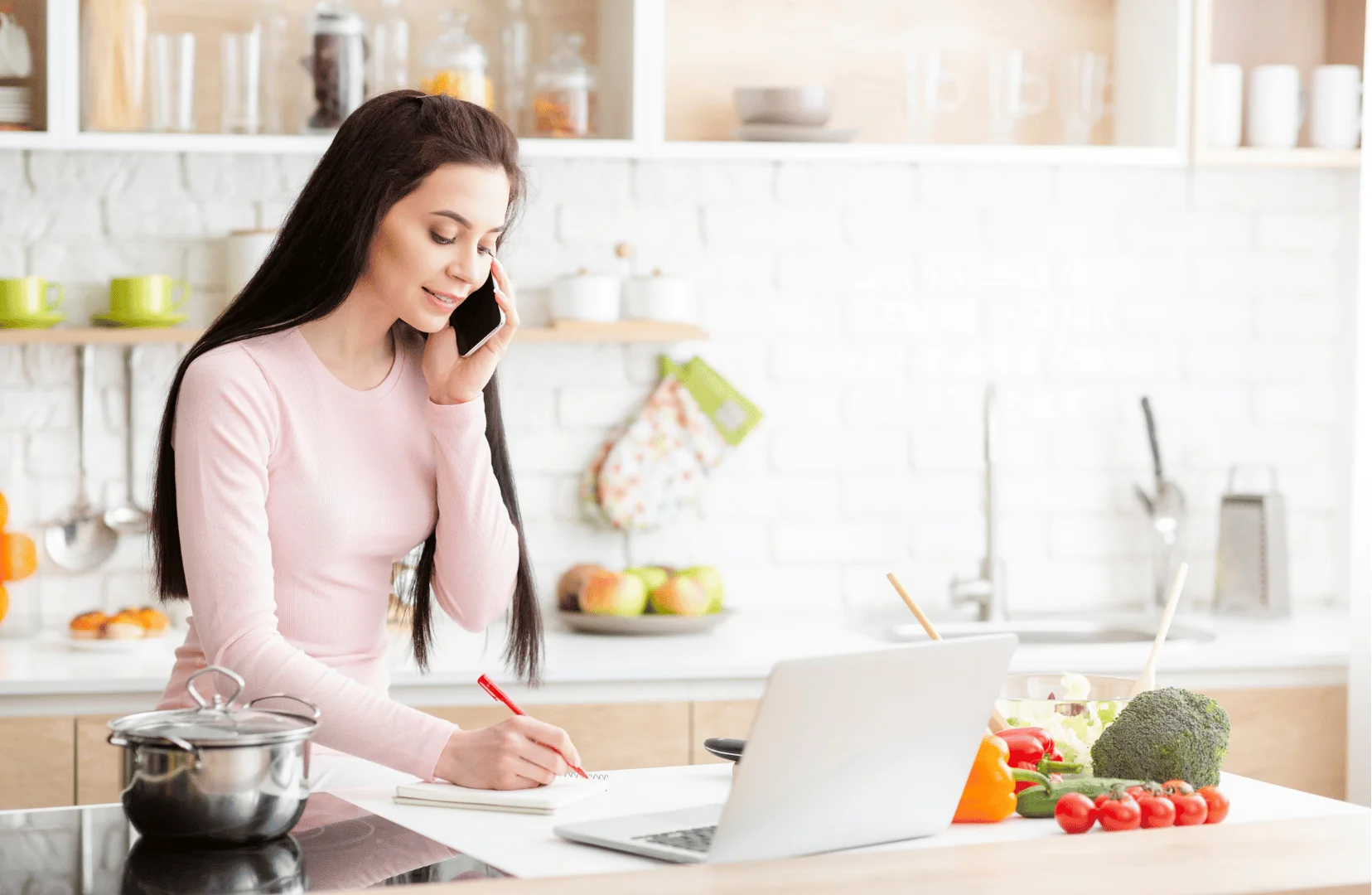 Emprendedora en su cocina gestionando su negocio con laptop y teléfono